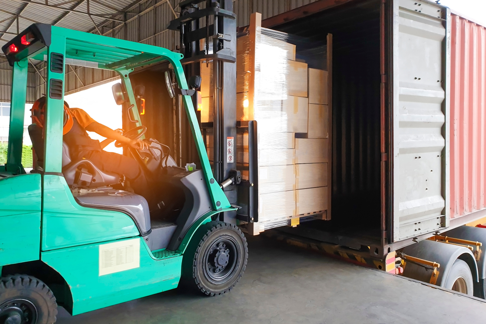 Forklift operator loading freight from the warehouse onto a tractor trailer