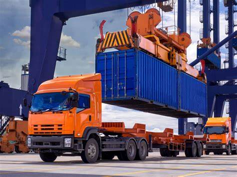 Crane operator loading container at port yard for truck transport