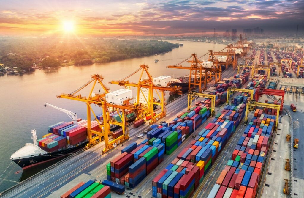 Port yard with ships docked alongside and numerous containers arranged in the yard